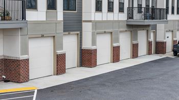 A street view of a row of garages with a car parked on the right side